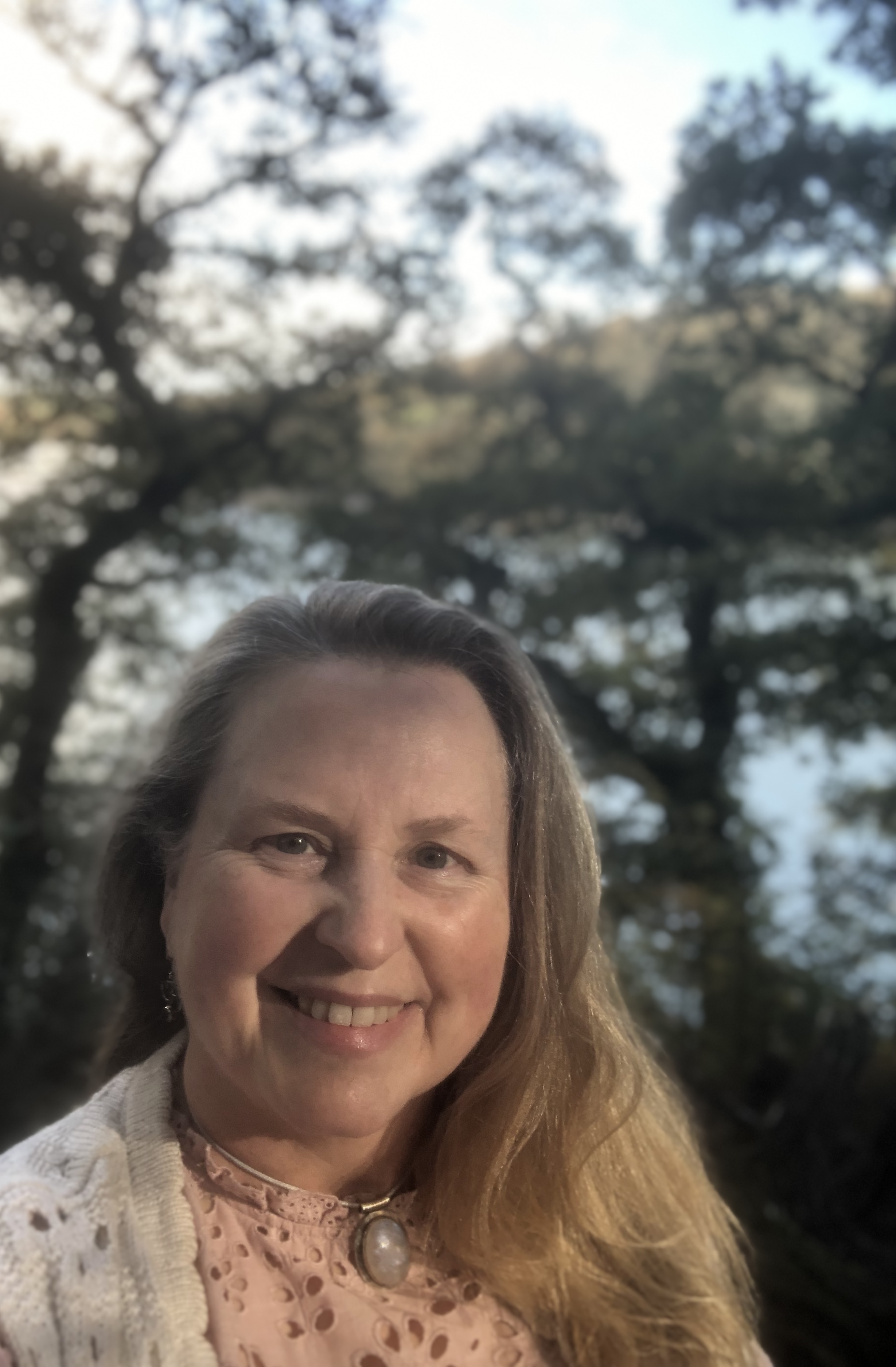 Jayne smiling in dappled woodland light